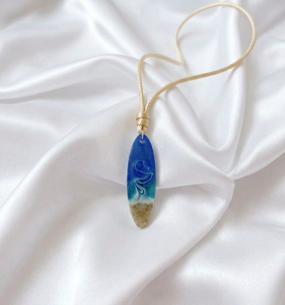 Adjustable rope necklace with handcrafted resin surfboard pendant filled with South African beach sand