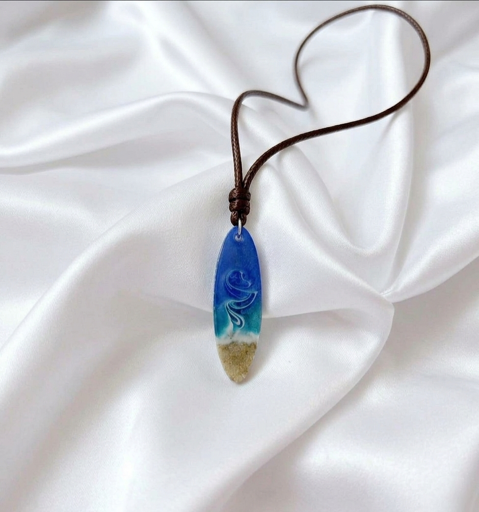 Adjustable rope necklace with handcrafted resin surfboard pendant filled with South African beach sand